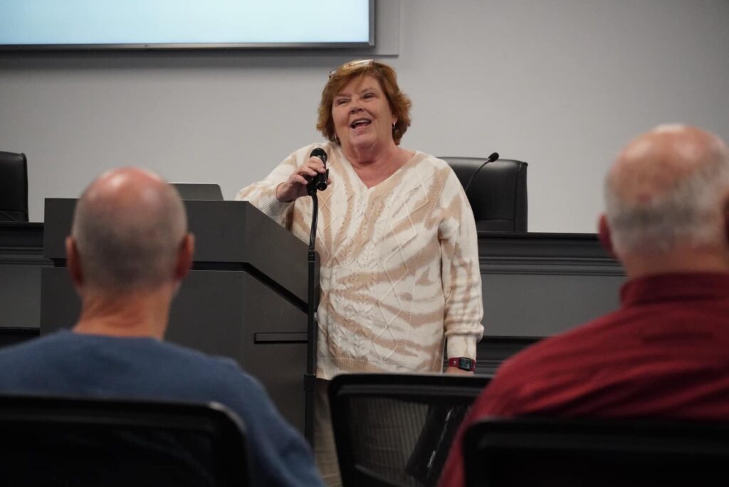 Dr. Honeycutt holding a microphone and smiling while speaking at an event.